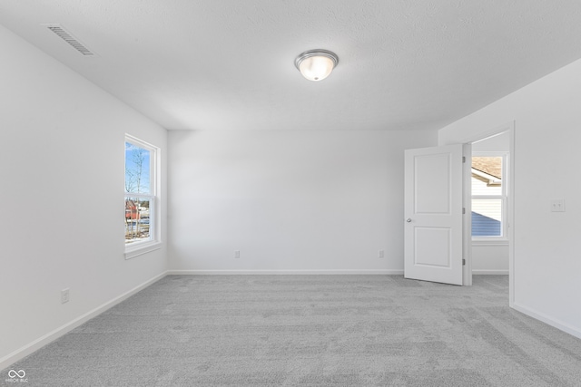 carpeted spare room featuring a healthy amount of sunlight and a textured ceiling