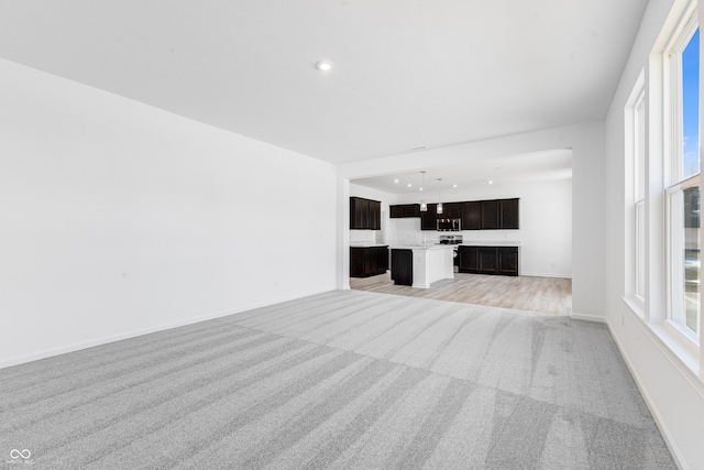 unfurnished living room featuring light carpet and plenty of natural light