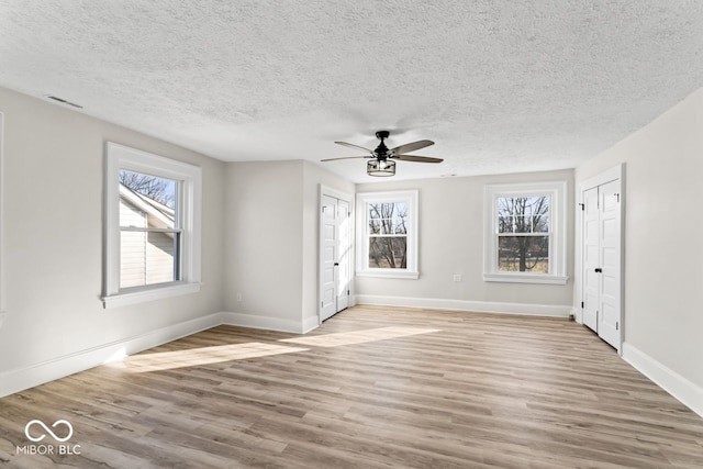 interior space featuring visible vents, baseboards, ceiling fan, wood finished floors, and a textured ceiling