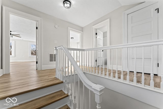 stairs with visible vents, baseboards, wood finished floors, and a ceiling fan