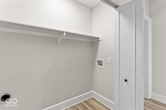 clothes washing area featuring laundry area, baseboards, light wood-style floors, and washer hookup