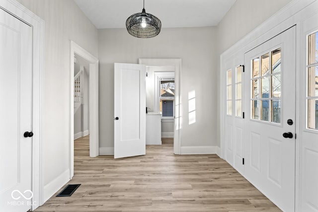 foyer entrance featuring visible vents, baseboards, and light wood finished floors