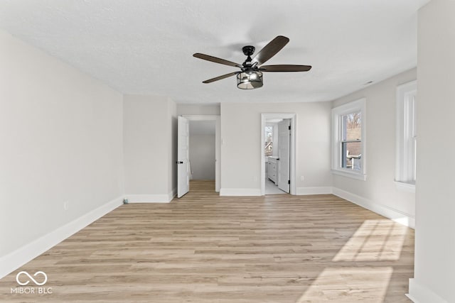 unfurnished bedroom with light wood finished floors, a textured ceiling, ensuite bathroom, and baseboards