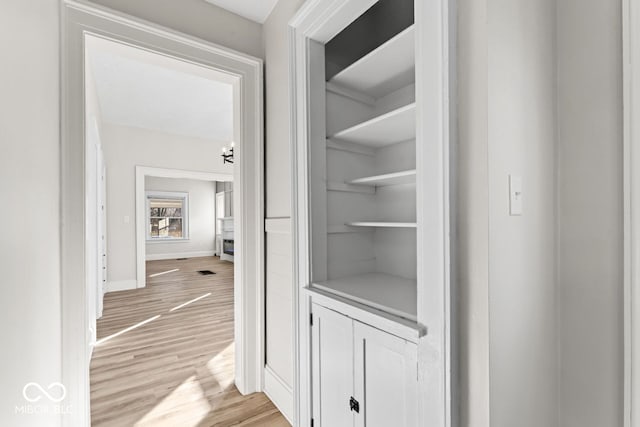 hall featuring visible vents, light wood-style flooring, and baseboards