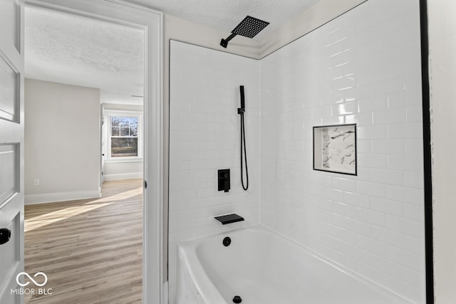 bathroom with shower / bath combination, wood finished floors, baseboards, and a textured ceiling