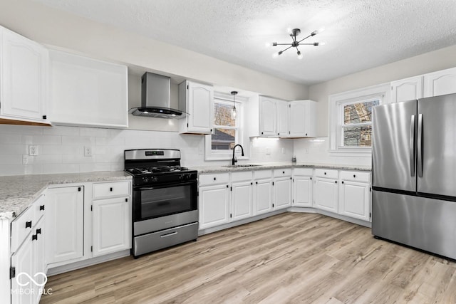 kitchen featuring light wood-style flooring, stainless steel appliances, white cabinetry, wall chimney exhaust hood, and a sink