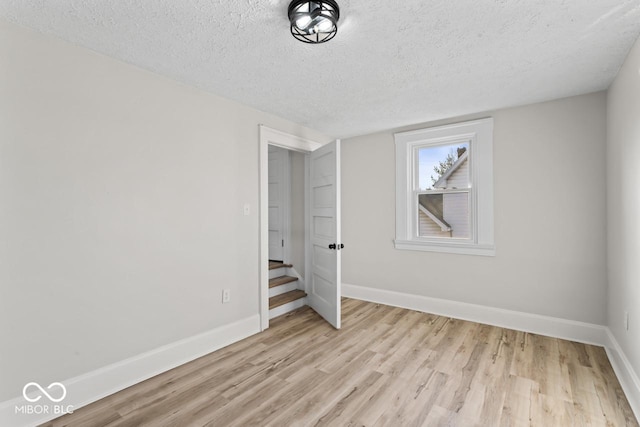 unfurnished bedroom with a textured ceiling, baseboards, and light wood-style floors