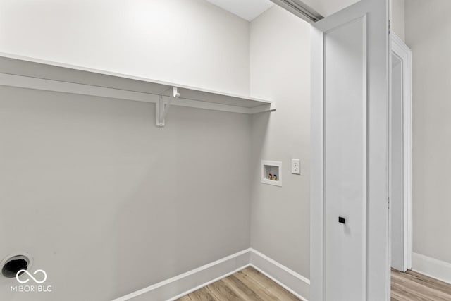 laundry area featuring light wood finished floors, laundry area, hookup for a washing machine, and baseboards