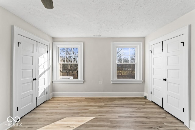 unfurnished bedroom featuring baseboards, multiple windows, and light wood-style floors