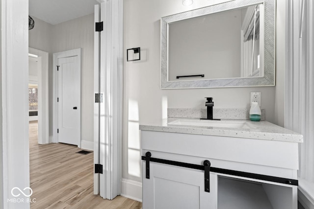 bathroom featuring vanity, wood finished floors, visible vents, and baseboards