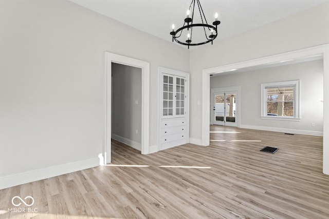 unfurnished dining area with baseboards, an inviting chandelier, and wood finished floors