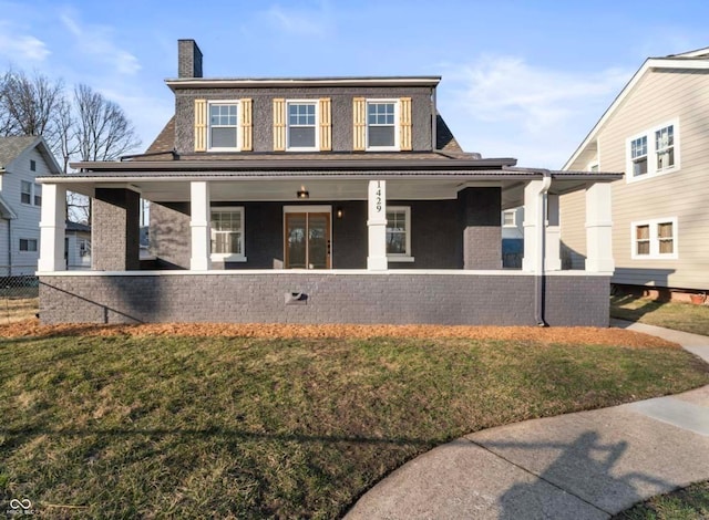 view of front facade featuring a chimney, brick siding, covered porch, and a front yard