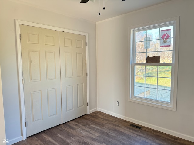 unfurnished bedroom featuring dark wood-type flooring, ceiling fan, and a closet