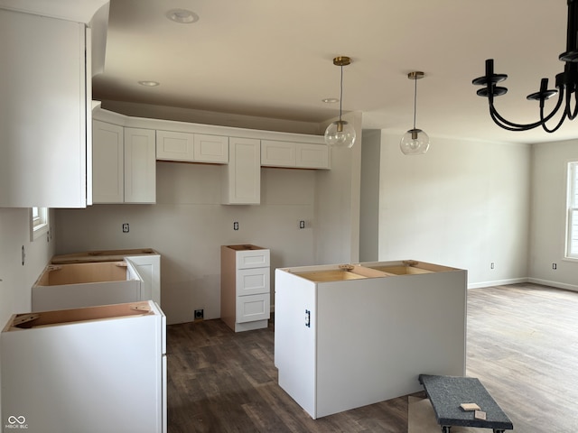 kitchen with white cabinets, dark wood-type flooring, decorative light fixtures, and a kitchen island