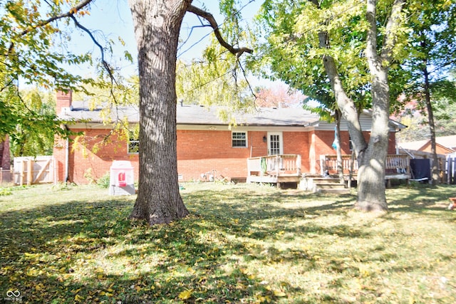 back of property with brick siding, a lawn, and a wooden deck