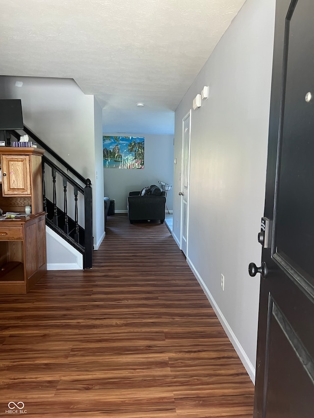 hall featuring dark wood-type flooring and a textured ceiling