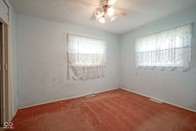 spare room featuring a wealth of natural light, carpet flooring, and ceiling fan