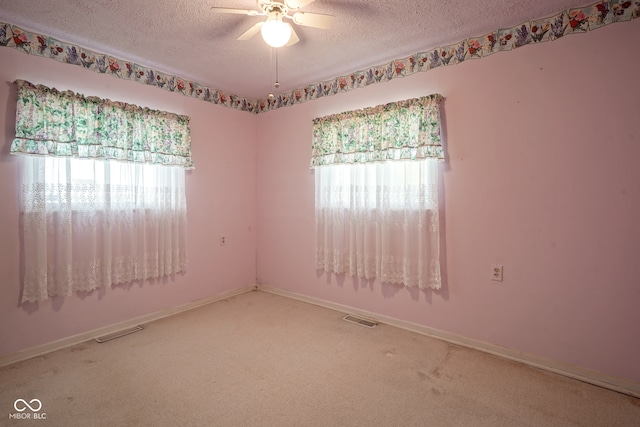 empty room with ceiling fan, a textured ceiling, and plenty of natural light