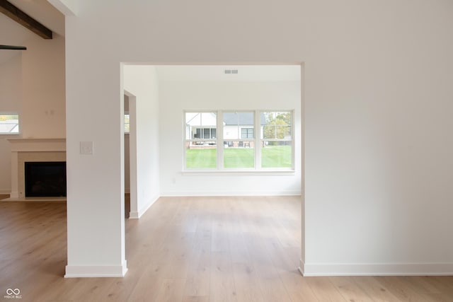 hall featuring baseboards, light wood finished floors, and beam ceiling