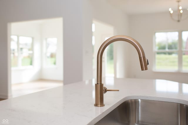room details with a sink, light stone countertops, and a chandelier