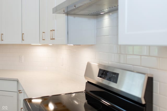 kitchen with wall chimney range hood, light countertops, electric stove, white cabinetry, and decorative backsplash