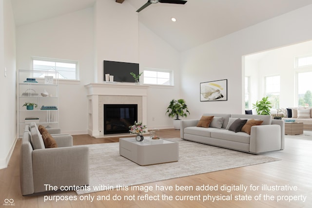 living area featuring a ceiling fan, high vaulted ceiling, a glass covered fireplace, and a wealth of natural light