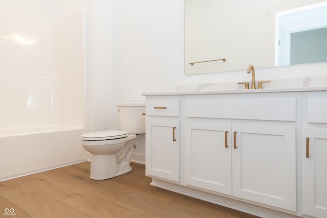full bath with washtub / shower combination, vanity, toilet, baseboards, and wood finished floors
