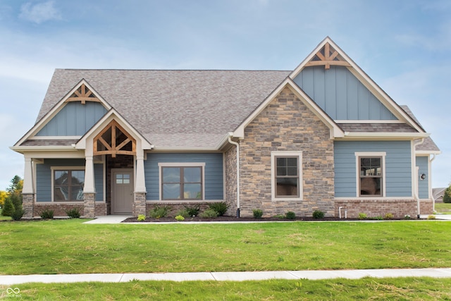 craftsman inspired home with a shingled roof, a front lawn, board and batten siding, and stone siding