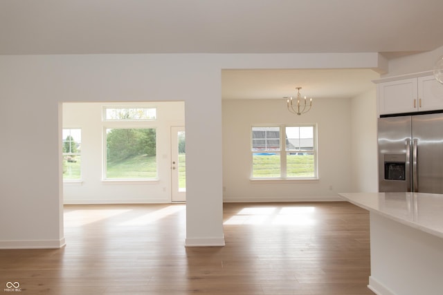 interior space with baseboards, light wood finished floors, and a notable chandelier