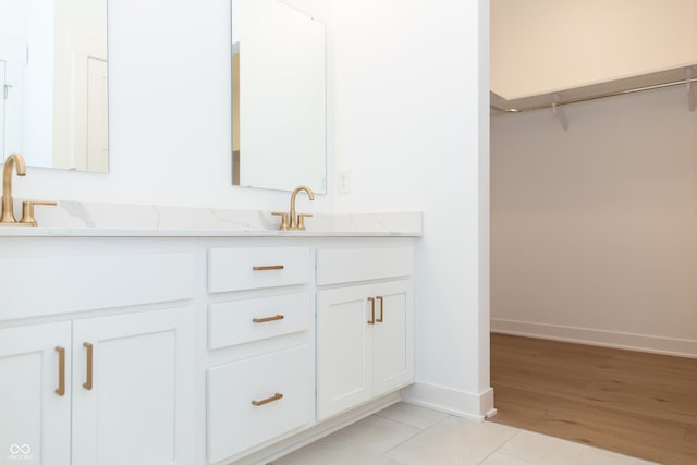 full bathroom featuring baseboards, double vanity, a sink, and wood finished floors
