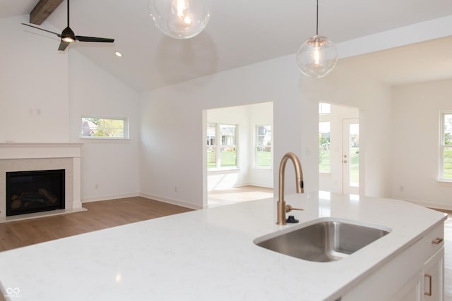 kitchen featuring a sink, vaulted ceiling with beams, light stone countertops, and open floor plan