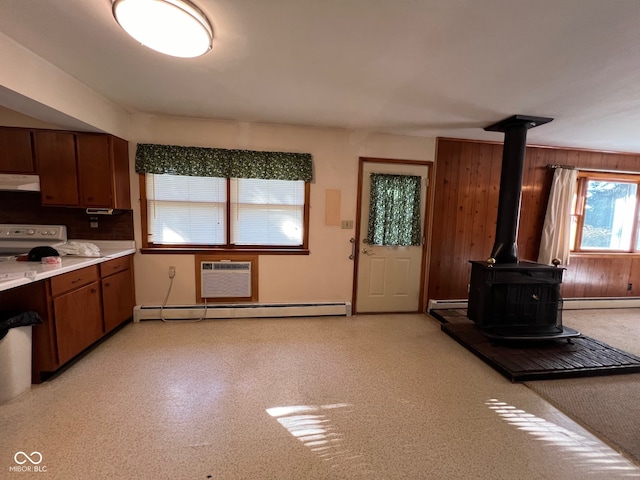 kitchen with a wall mounted air conditioner, a wood stove, ventilation hood, a baseboard radiator, and wood walls