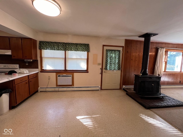 kitchen featuring a baseboard heating unit, ventilation hood, stove, a wall mounted air conditioner, and a wood stove