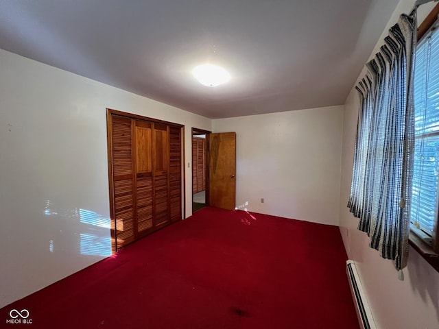 unfurnished bedroom featuring baseboard heating, carpet floors, multiple windows, and a closet