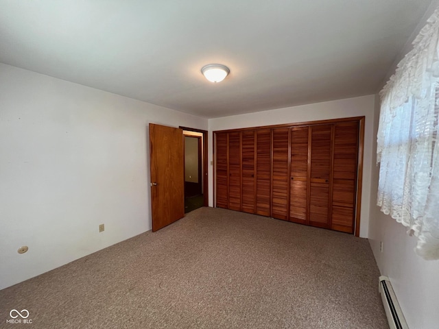 unfurnished bedroom featuring a baseboard heating unit, carpet flooring, and a closet
