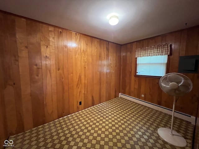 empty room featuring a baseboard heating unit and wood walls