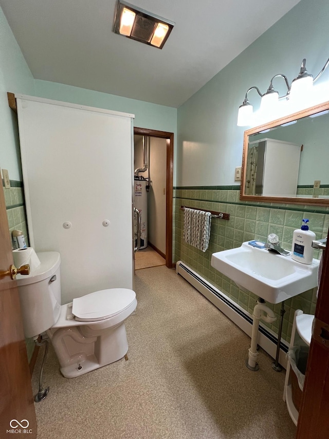 bathroom with a sink, toilet, tile walls, baseboard heating, and water heater