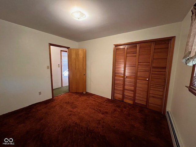 unfurnished bedroom featuring a baseboard heating unit, carpet flooring, and a closet