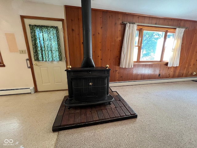 interior details featuring a baseboard heating unit, wood walls, a wood stove, and baseboards