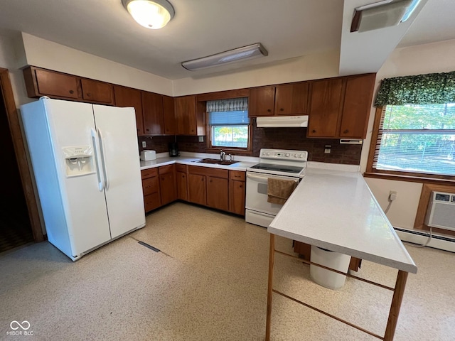 kitchen with a sink, tasteful backsplash, white appliances, light countertops, and under cabinet range hood
