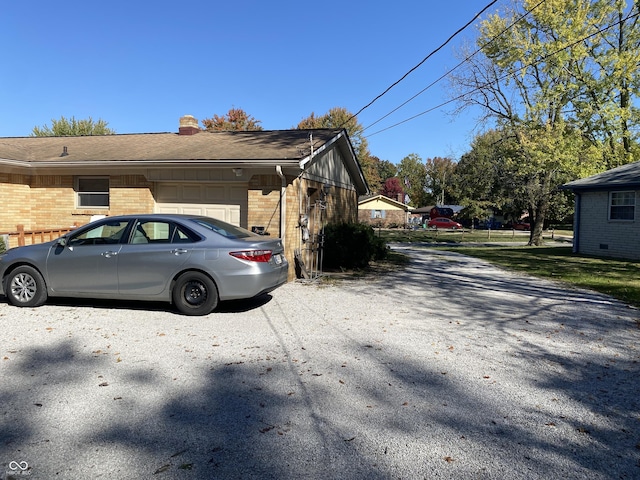 view of property exterior with brick siding, an attached garage, and a chimney