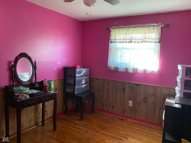 misc room featuring ceiling fan, hardwood / wood-style flooring, and wood walls