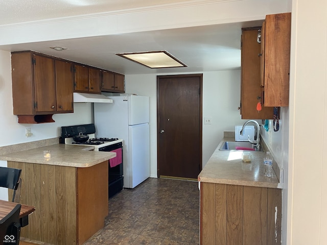 kitchen with a sink, freestanding refrigerator, range with gas stovetop, light countertops, and under cabinet range hood