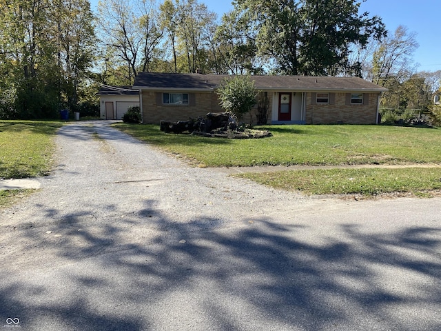 ranch-style house featuring gravel driveway, a front lawn, and a garage