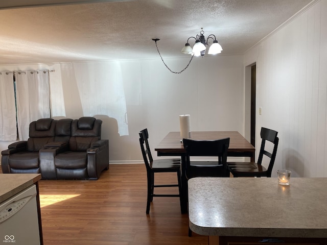 dining space with an inviting chandelier, wood finished floors, crown molding, baseboards, and a textured ceiling
