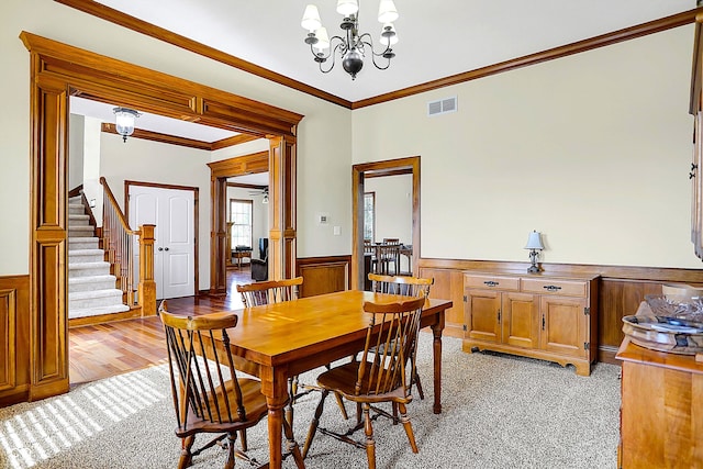 dining area featuring crown molding, light carpet, and a notable chandelier