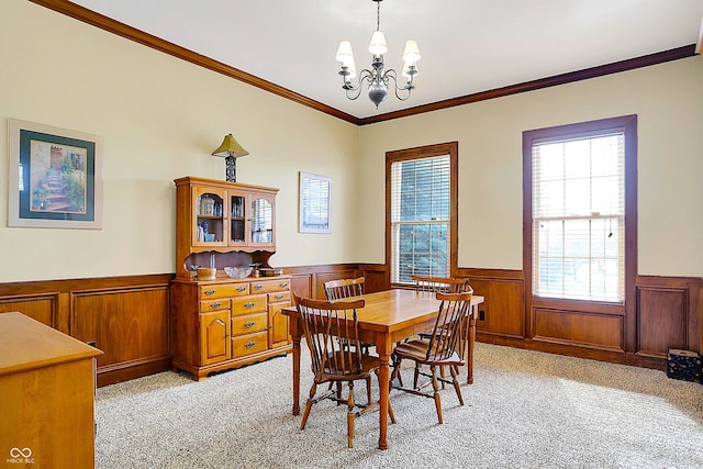 carpeted dining area with ornamental molding and a chandelier