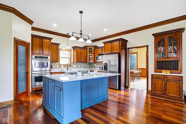 kitchen featuring crown molding, a kitchen island, pendant lighting, and appliances with stainless steel finishes