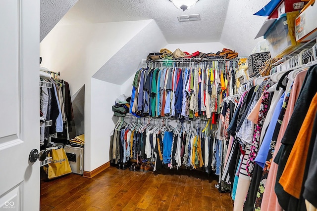 spacious closet with dark wood-type flooring and vaulted ceiling