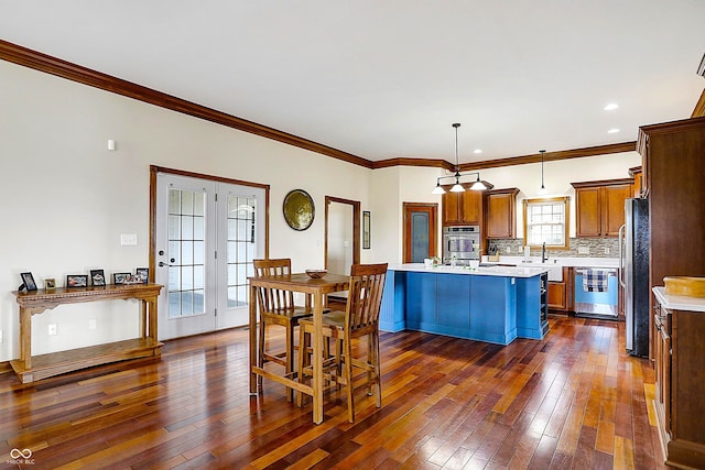 kitchen featuring pendant lighting, backsplash, stainless steel appliances, a center island, and ornamental molding